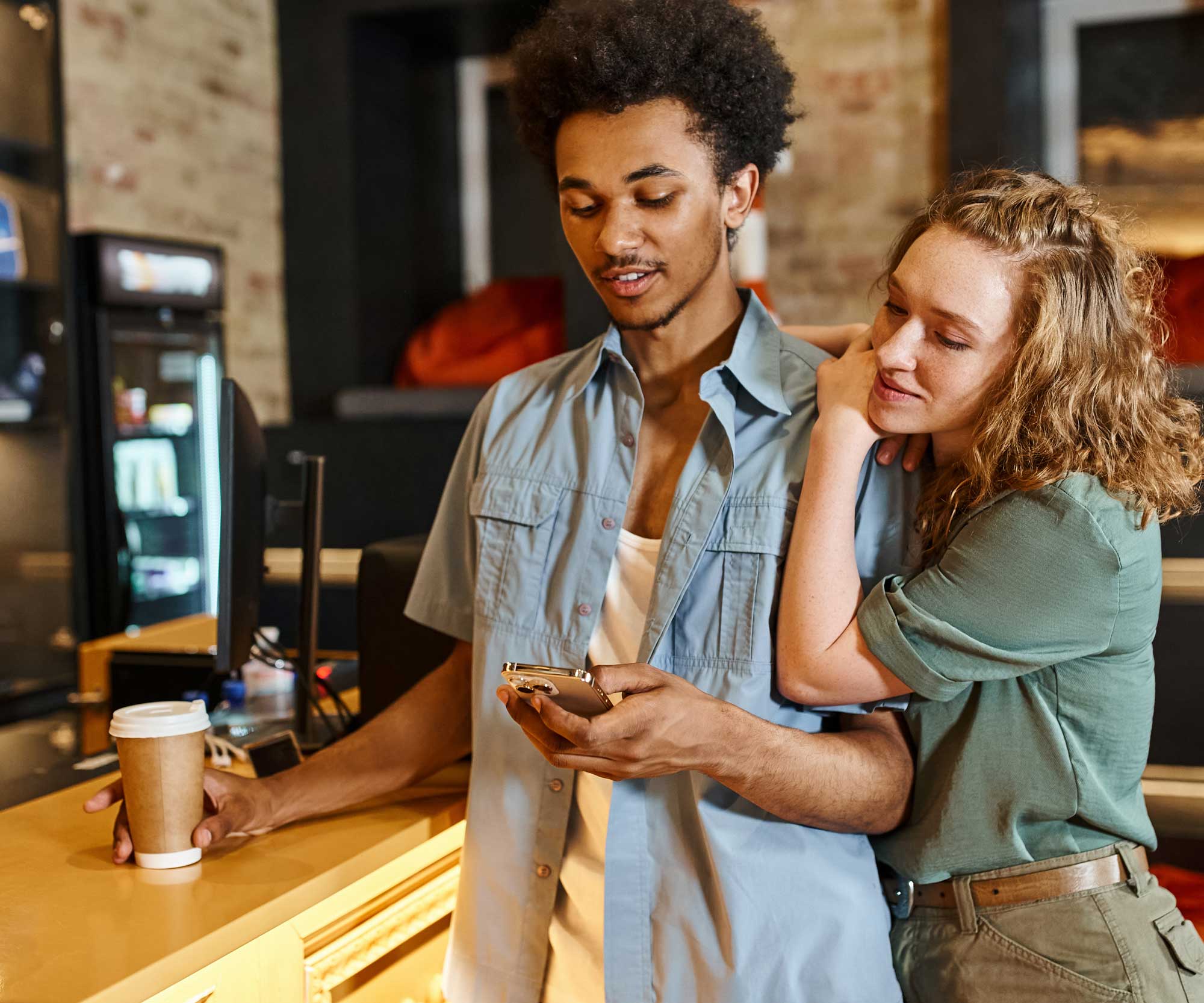Couple standing by a bar in a hostel looking at a phone